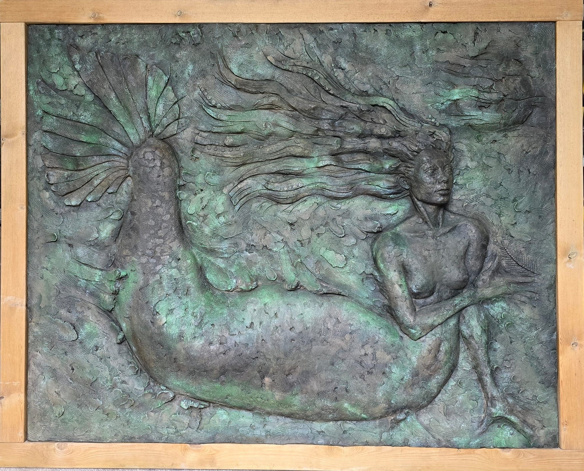 Bronze mermaid wall sculpture with flowing hair in wooden frame